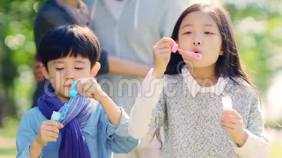 两个亚洲孩子在公园户外吹泡泡视频的预览图
