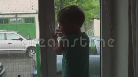 一个男孩站在窗户附近看着街上的雨雨停游戏视频的预览图