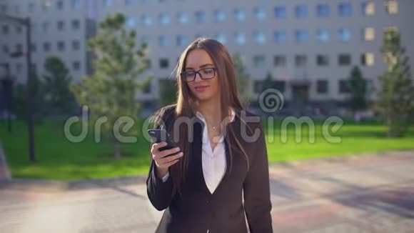 美丽的年轻女商人或穿着白色衬衫的学生在城市里使用现代智能手机专业人士视频的预览图