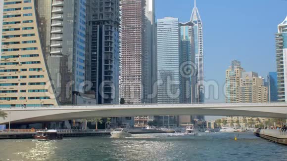 游艇和游艇在迪拜阳光明媚的天气里漂浮着现代的桥视频的预览图