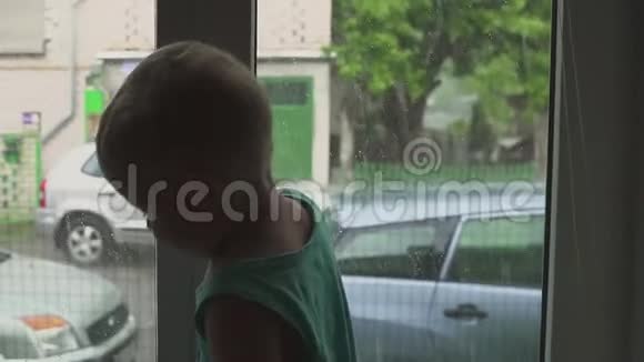 一个男孩站在窗户附近看着街上的雨雨停游戏视频的预览图
