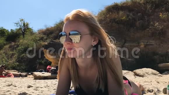 美丽的女孩戴着太阳镜躺在海滩上视频的预览图