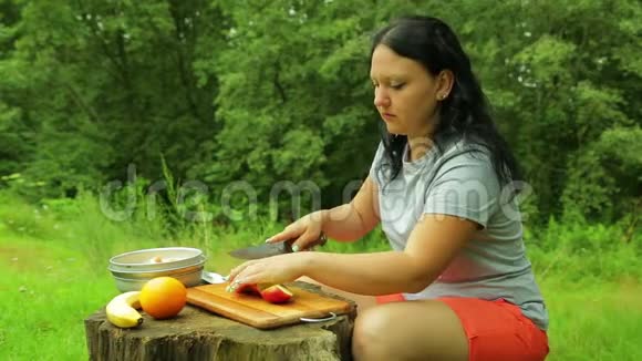 一个年轻的女人把一个苹果切成碎片用种子清洗它视频的预览图