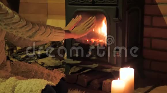 特写女人用火暖暖他的手用玻璃封闭的壁炉视频的预览图