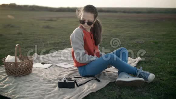 一个可爱的年轻女孩在野餐时用老式相机拍照视频的预览图