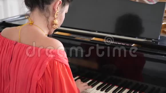 女音乐家穿着优雅的服装和别致的耳环缓慢地弹钢琴视频的预览图