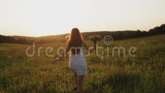 穿着白色裙子的漂亮女孩在乡间田野里奔跑在阳光下的草地上享受着阳光微笑着视频的预览图