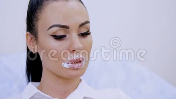特写镜头病人坐在美容诊所嘴唇上有一个叠加的麻醉剂奶油垫上面覆盖着视频的预览图