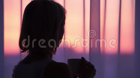 日出时喝咖啡的女人女人的剪影视频的预览图