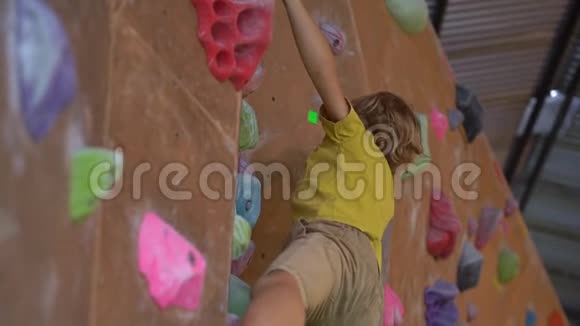 一个小男孩在一个巨石攀爬体育馆里爬墙时慢镜头视频的预览图