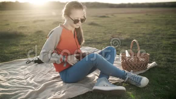 一个戴太阳镜的年轻女孩安排了一次自然野餐视频的预览图