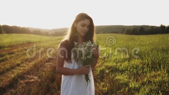 身着白衣的年轻女子站在草地上手捧鲜花对着镜头微笑视频的预览图