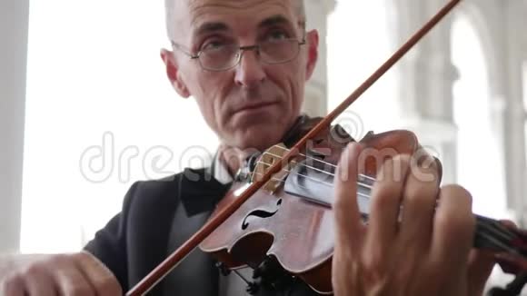 戴眼镜的老人在室内玩木小提琴画像视频的预览图