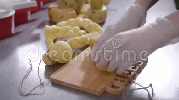 奶酪制造商正在一张桌子上的木制砧板上切割最终的奶酪产品并特写了手视频的预览图