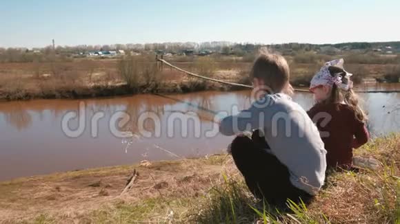 兄妹俩坐在村里的河岸上玩耍后景视频的预览图