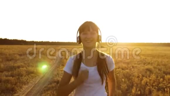 戴着耳机的运动女孩正在慢跑一个年轻女孩正在日落时训练听音乐视频的预览图
