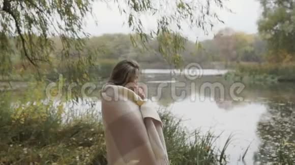 肩上有格子手里拿着杯子的美女在河边欣赏风景视频的预览图