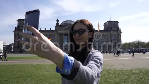 年轻的微笑女性自画像智能手机帝国大厦柏林关闭视频的预览图