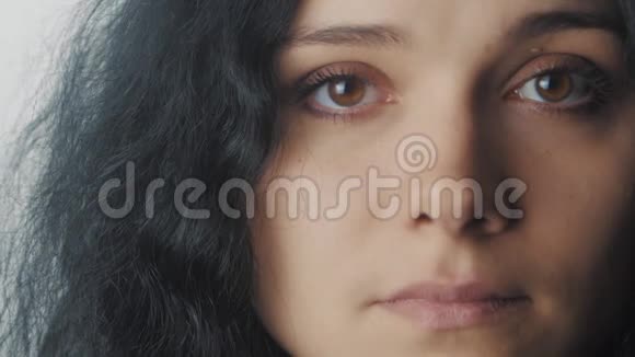 在白色背景下闭上棕色眼睛的女人的肖像视频的预览图