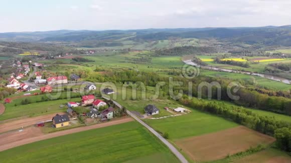 在一个有小房子的村庄里空中无人机可以看到绿田丘陵和树木波兰视频的预览图