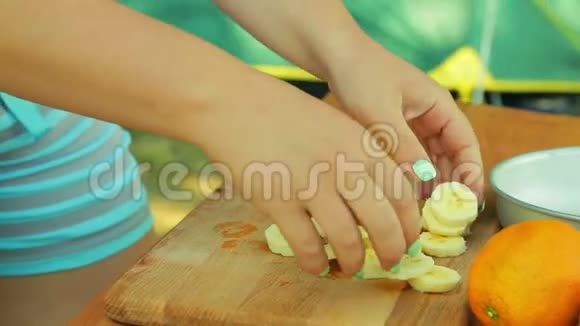 一个年轻的女人在一个带有水果沙拉的碗里安排了一个香蕉的碎片来野餐视频的预览图