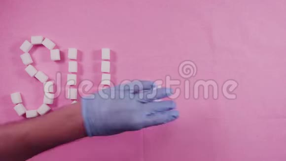 单词糖是由精炼的糖块在粉红色的背景上排列出来的龋齿的概念视频的预览图
