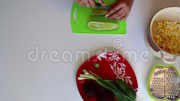 一个女人正在切切割板上的黄瓜盘子旁边是蔬菜汤煮甜菜和洋葱的其他原料视频的预览图