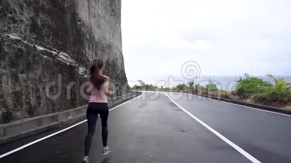 女孩在岩石路上奔跑在悬崖被海洋冲走视频的预览图