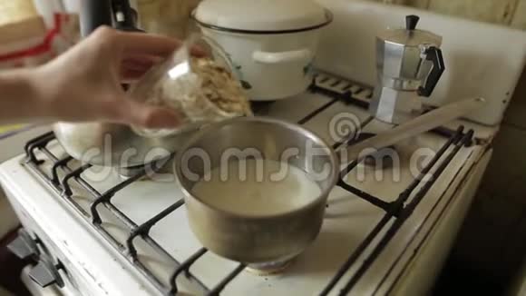 健康素食早餐燕麦粥一个白人女人的手把大燕麦片从玻璃杯里倒入金属视频的预览图