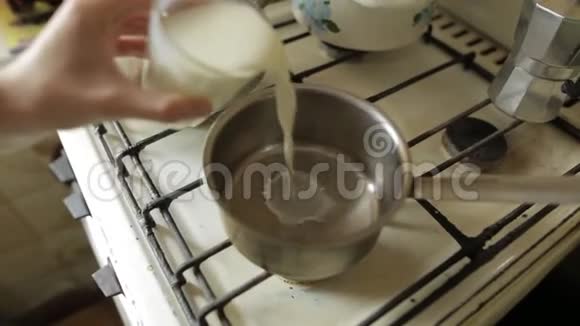 牛奶被倒入厨房的炉子上的锅中小女孩把牛奶倒在锅里做饭健康食品视频的预览图