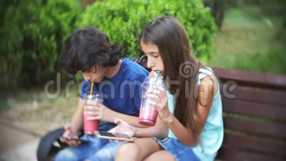 网络成瘾的概念青少年男孩和女孩使用他们的智能手机坐在公园的长凳上驼背视频的预览图