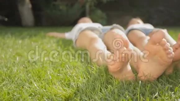在炎热的夏日两只女孩的脚躺在草地上视频的预览图