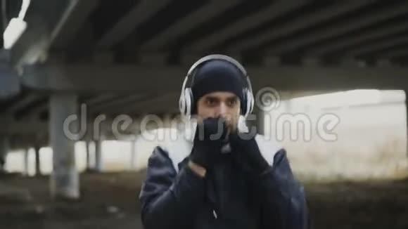 青年拳击手手持射击耳机训练拳打脚踢城市位置户外冬季视频的预览图