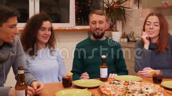 快乐的朋友坐在节日的餐桌旁在家庆祝新年晚会视频的预览图