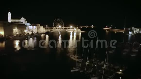 4k慢淘夜空中无人机帆船港和沿海城镇的镜头视频的预览图