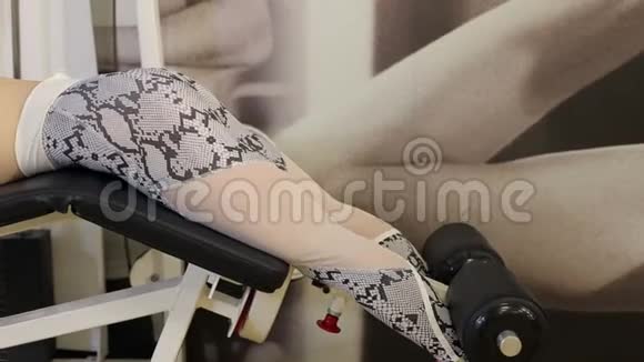 女孩在健身房的印刷机上做腿的运动视频的预览图