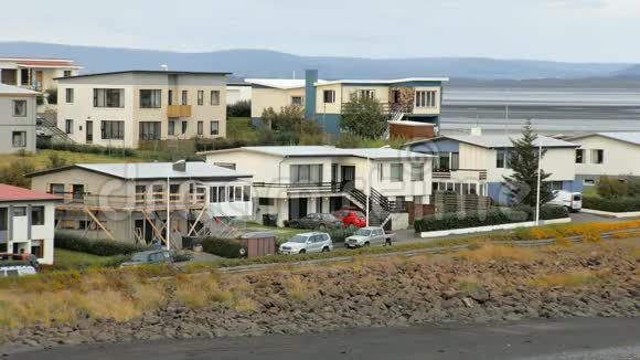 在冰岛小镇郊区河流和山脉的建筑和停放的汽车都是背景视频的预览图