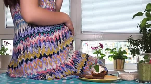 怀孕女性的手抚摸着肚子快乐的女人吃着有食欲的蛋糕视频的预览图