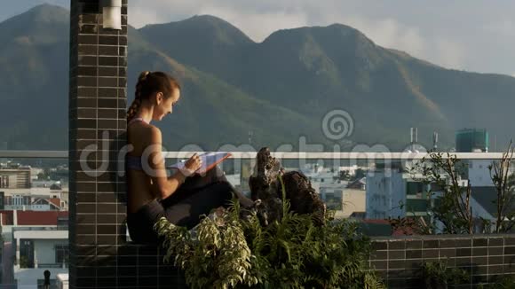 女孩坐在露台屏障上写日记在山上视频的预览图