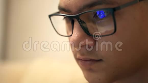 在现代办公室里戴眼镜晚上通过笔记本电脑工作的年轻时髦男人的特写镜头男性的特写镜头视频的预览图
