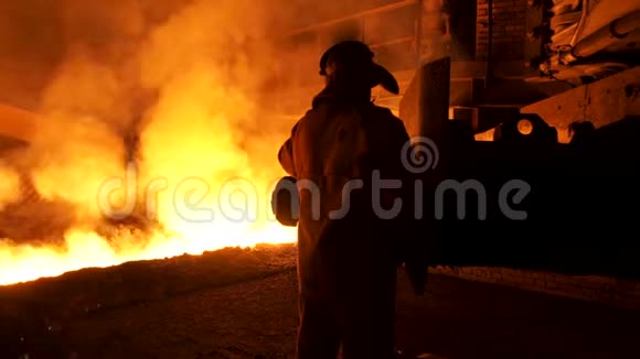穿着特殊防护服的工人站在钢水附近有火花和蒸汽重工业概念视频的预览图