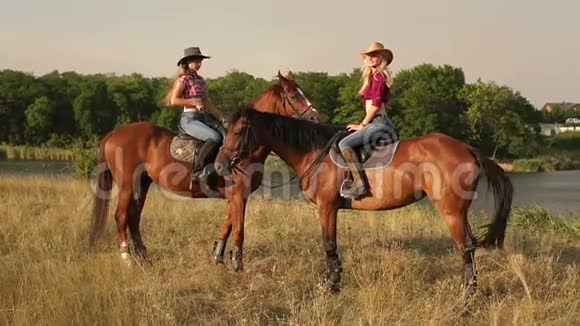 两个女孩骑着棕色的马在湖边视频的预览图