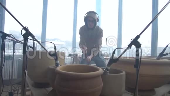戴眼镜和运动衫的鼓手在陶罐上打鼓视频的预览图