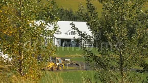 一个院子里的农夫和农用拖拉机房通过两个绿色的桦树可以看到视频的预览图