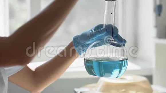 实验室实验中的一个烧瓶的特写蓝色液体旋转到烧瓶中视频的预览图