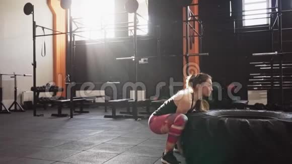 强壮的健身妇女在健身房做大轮胎翻转锻炼视频的预览图
