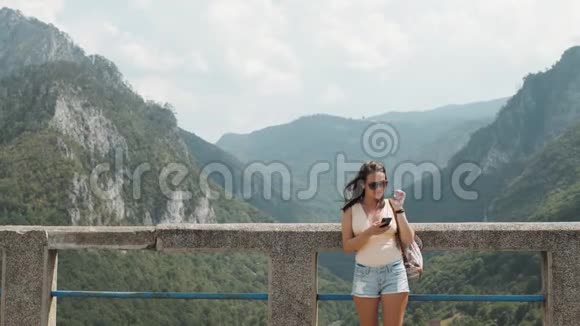 在黑山Djurdjevic桥上站着使用智能手机的旅游女孩旅行生活方式视频的预览图