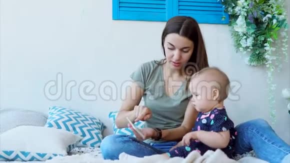 快乐的妈妈正在教小孩子使用智能手机坐在卧室里视频的预览图