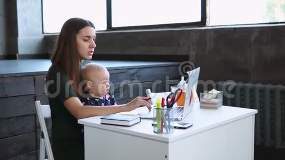 女商人正拿着婴儿在笔记本电脑前的贴纸上做笔记视频的预览图