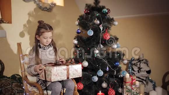 圣诞树旁美丽的小女孩打开一个礼物盒里面有圣诞老人送给的新年礼物视频的预览图